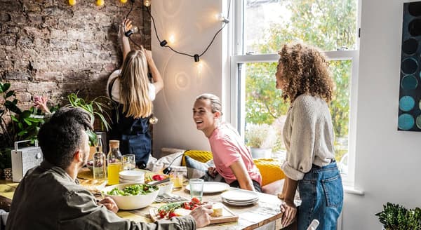 A diverse group of friends socializes during a meal together at home.