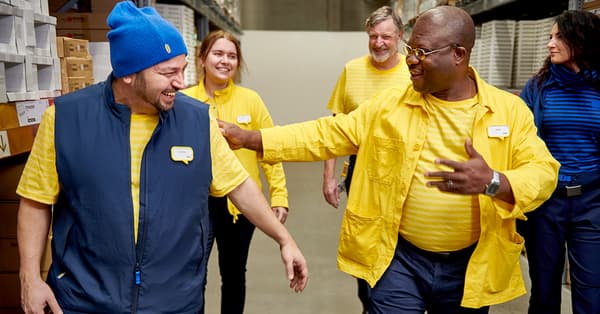 A diverse group of IKEA co-workers walking through the self service department of an IKEA store.