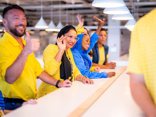 A diverse group of IKEA co-workers walking through the self service department of an IKEA store.
