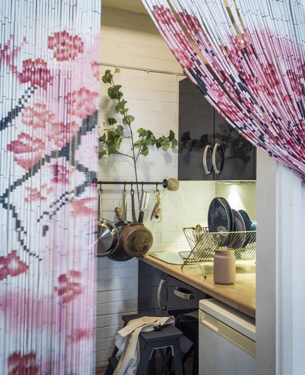 A door with a bead curtain leading to a small kitchen.