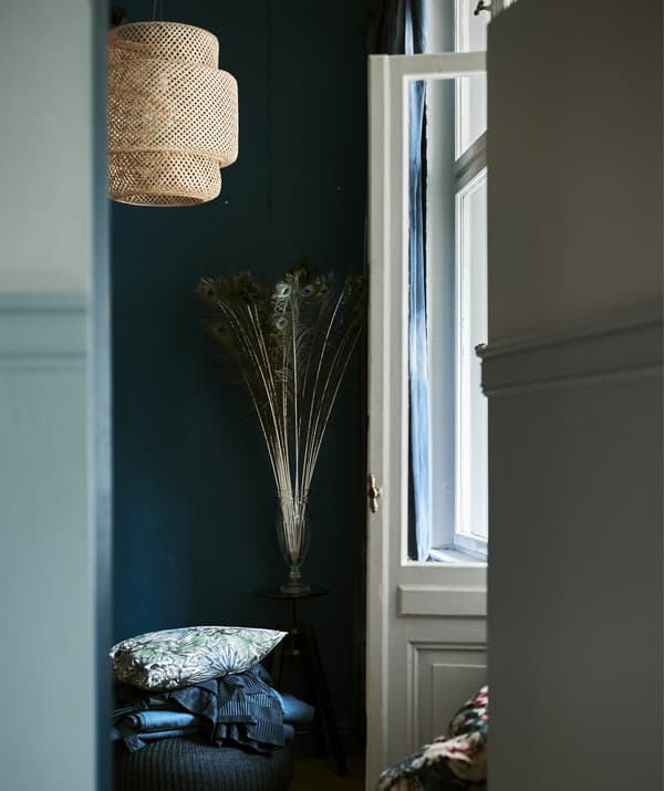 A doorway looking through to a dark room with a hanging lampshade.