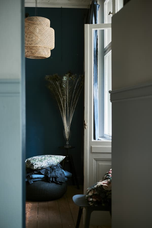 A doorway looking through to a dark room with hanging lampshade.