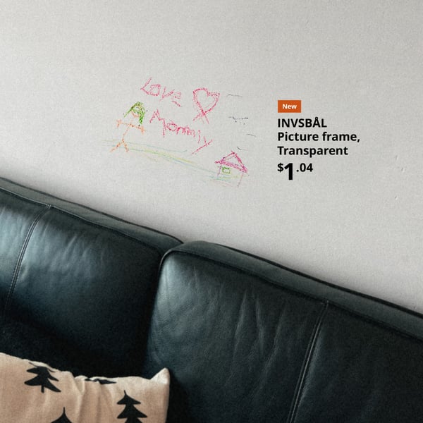 A drawing on a wall framed with an INVSBÅL Transparent Picture frame above a black leather couch