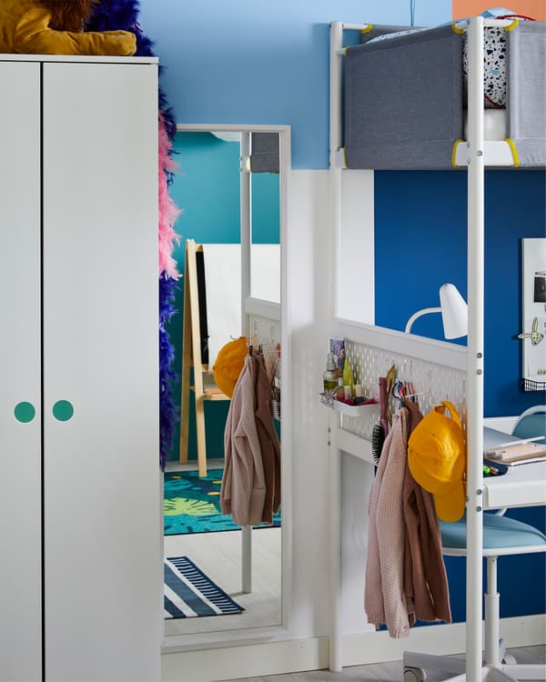 A dressing corner that includes a white mirror and white pegboard with accessories.
