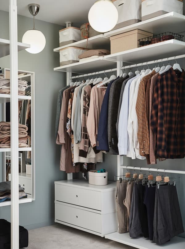 A dressing room is organised using drawers, hangers and baskets on the upper shelf.