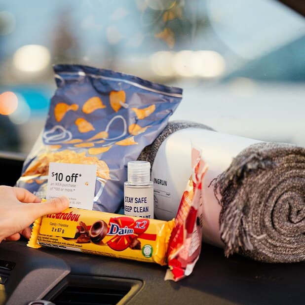 A Drive-In Kit containing a rolled gray blanket, potato chips, chocolates, candies, hand sanitizer and a coupon for IKEA.