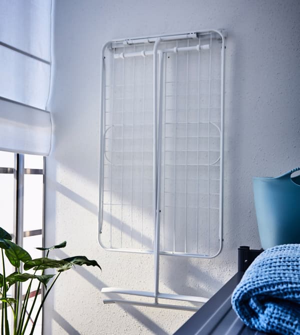 A drying rack is hung on the balcony wall with hooks to save space.