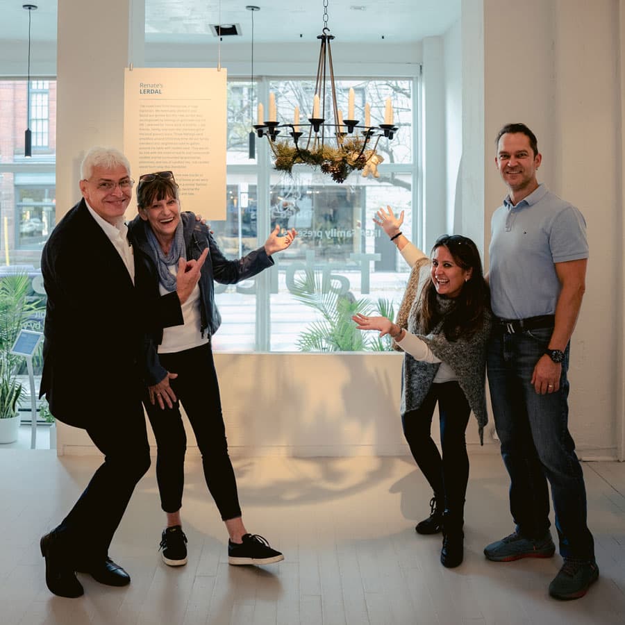 A family is posing for the camera while pointing to an IKEA LERDAL chandelier that is on display.