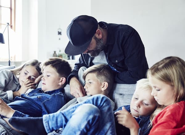A family of 6 relaxing on a sofa.