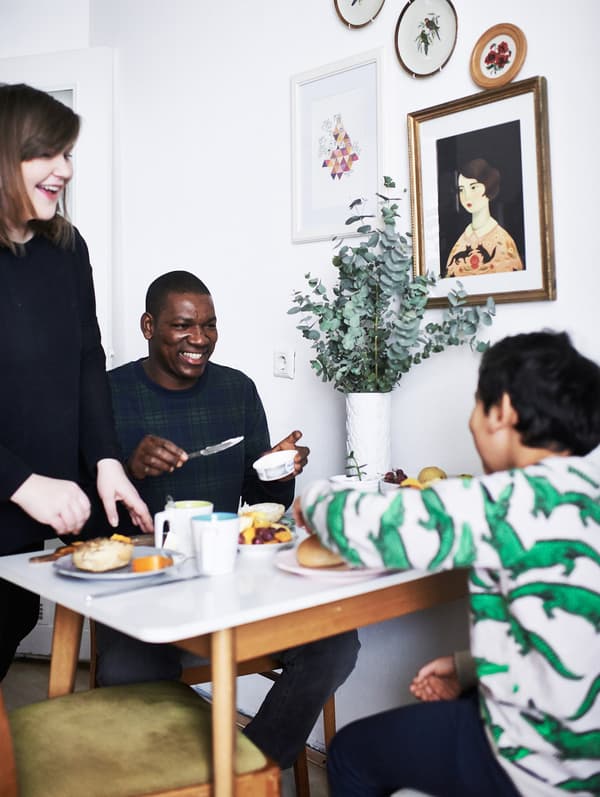 A family of three around the dining table, enjoying a small meal.
