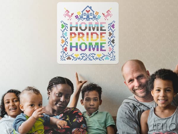 A family of two parents and four children sitting on a sofa with a Home Pride Home sign on the wall behind them.