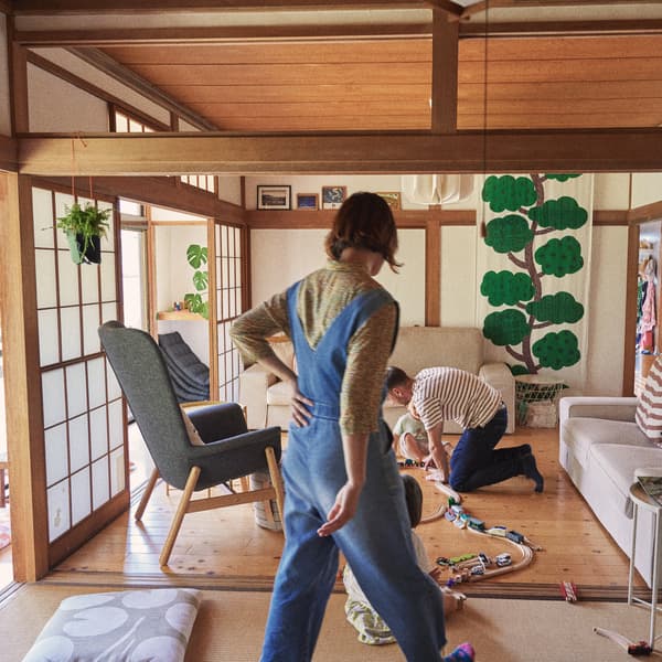 A family playing in a living room with a grey armchair, beige sofa, wood ceilings and floors.