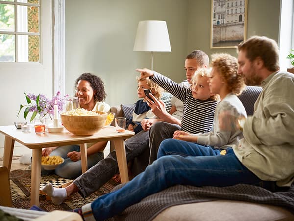 A family sitting on a sofa watching television.