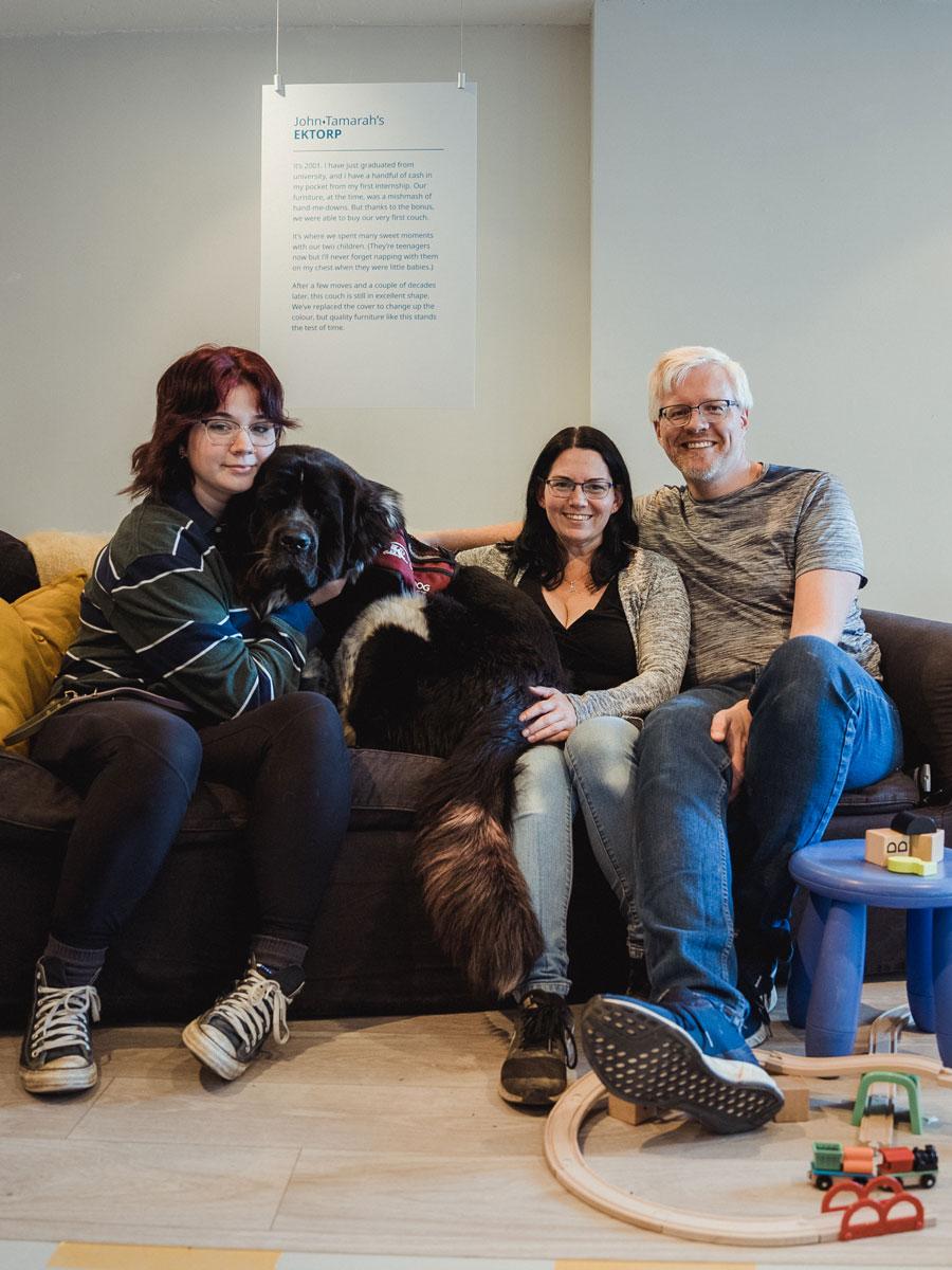 A family with a dog sit on an IKEA EKTORP sofa. A kids' stool and train set are placed by the sofa.