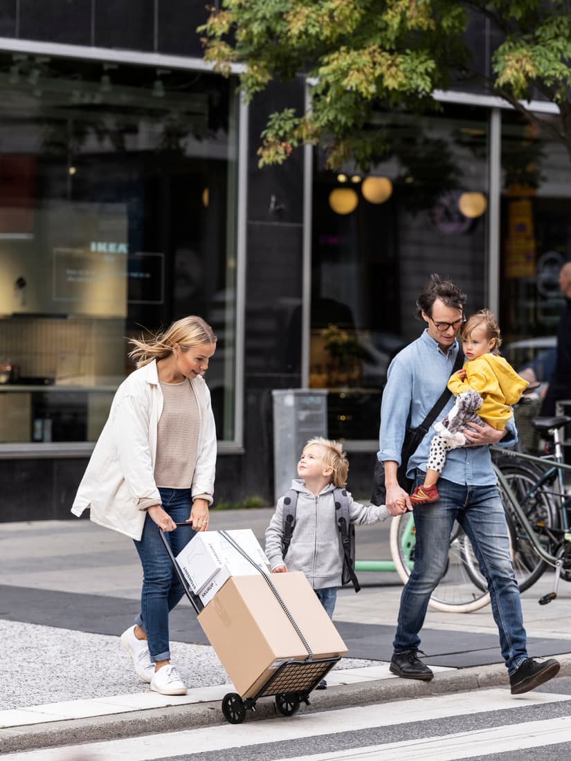 A family with two young children crossing the road with IKEA boxes.