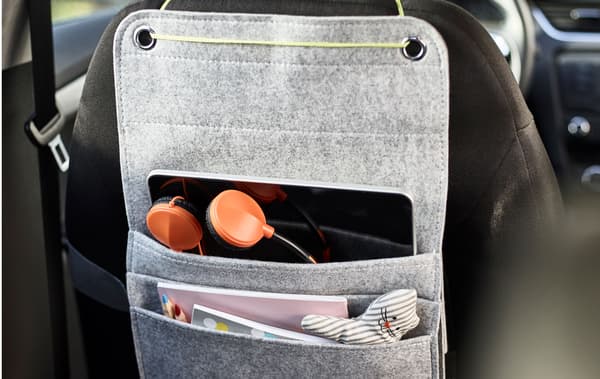 A felt hanging organiser tied to the back of a car seat with space for markers, coloring books and a tablet for kids as a diy car organiser.