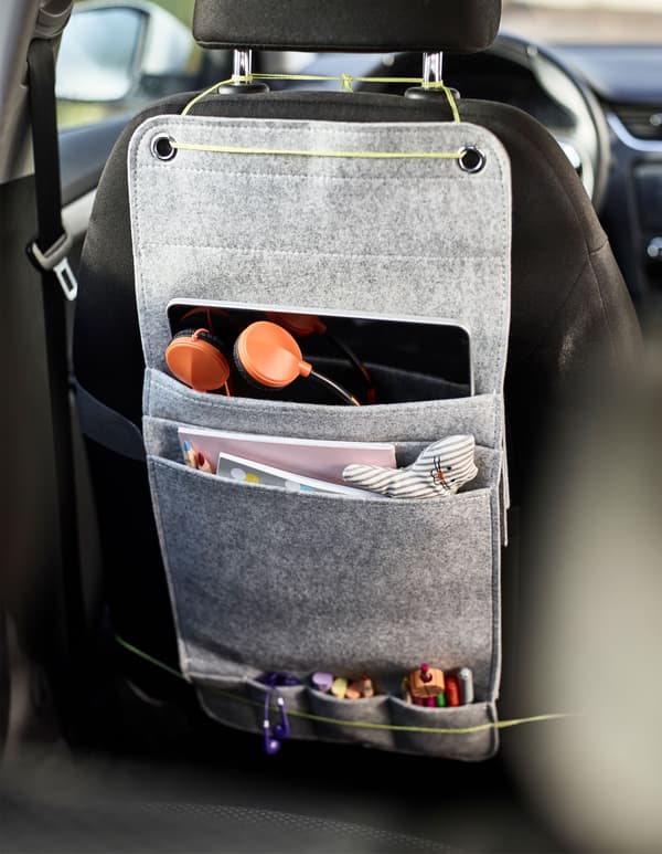 A felt hanging organiser tied to the back of a car seat with space for markers, coloring books and a tablet for kids as a diy car organiser.