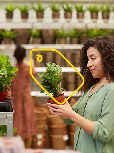 A female customer is holding a green plant in an IKEA store