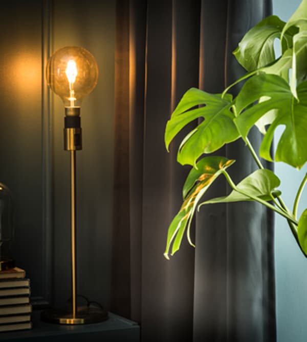 A floor lamp sits lit in front of a thick blackout curtain.