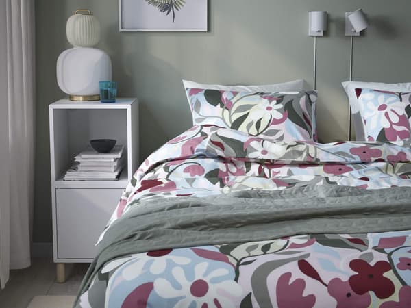 A floral bedding with maroon and blue shades in front of a green background.