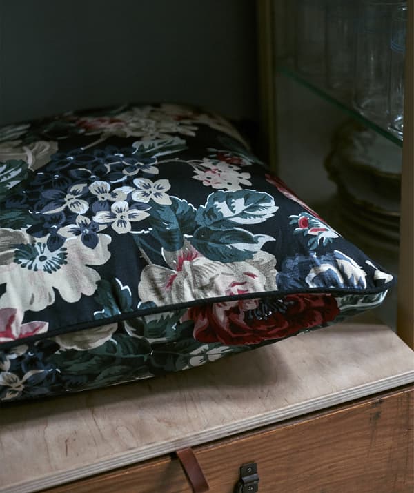 A floral-patterned cushion on a wooden box.
