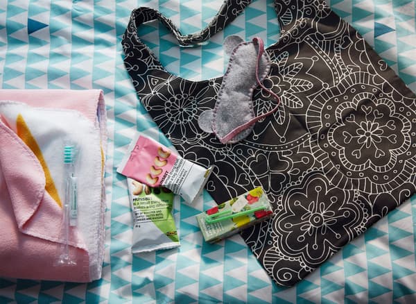 A floral-print IKEA VÄNSKAPLIG bag with snacks, juices and a sleep mask.