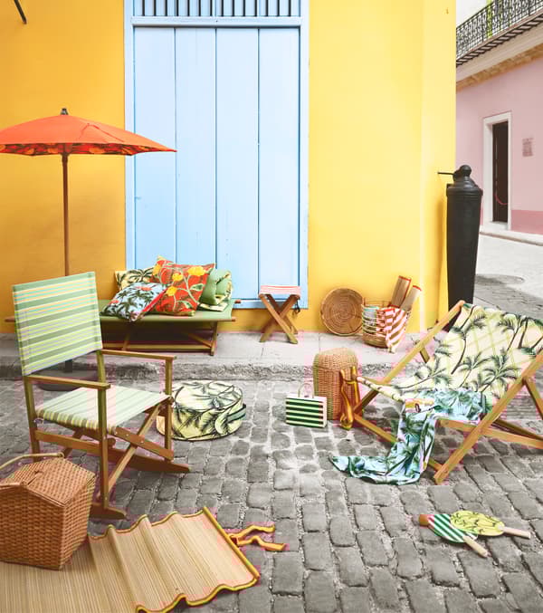 A foldable rocking chair and lounge chair with green patterns and prints, placed on a cobblestone surface.