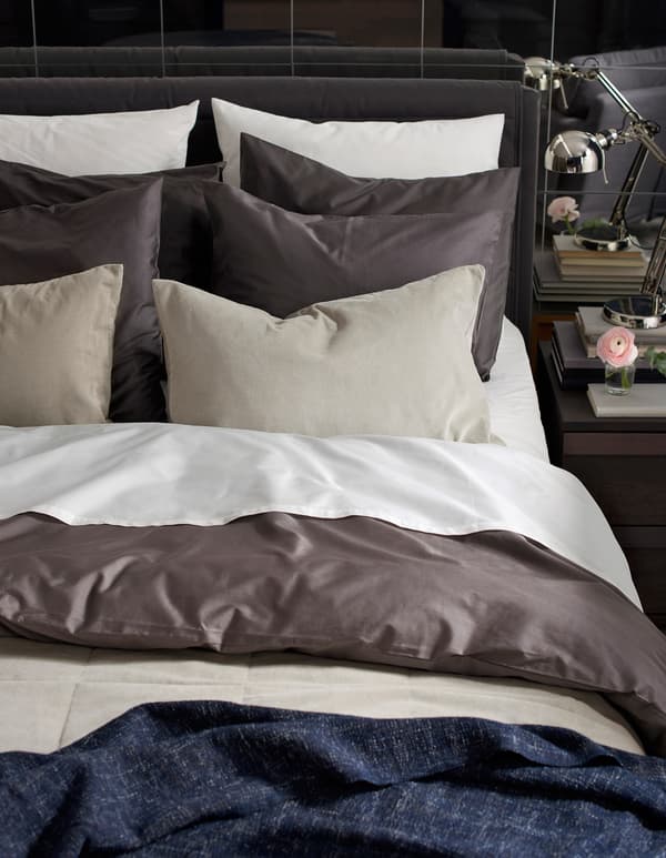 A freshly made bed with lots of pillows and layers of textiles.