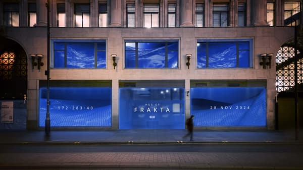 A front view of a street with blue display windows with the words HUS OF FRAKTA