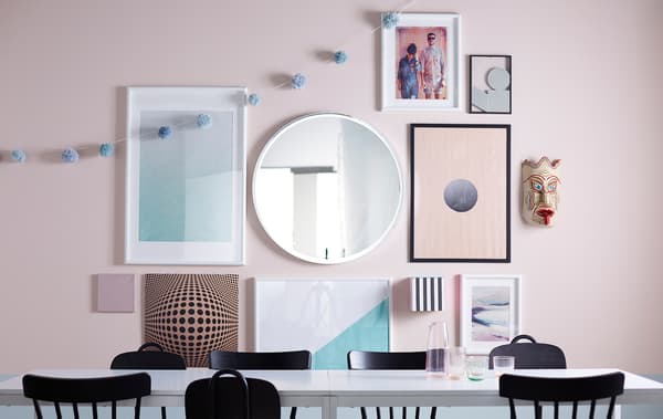 A gallery wall with different sizes of framed art, a mirror, and personal objects.