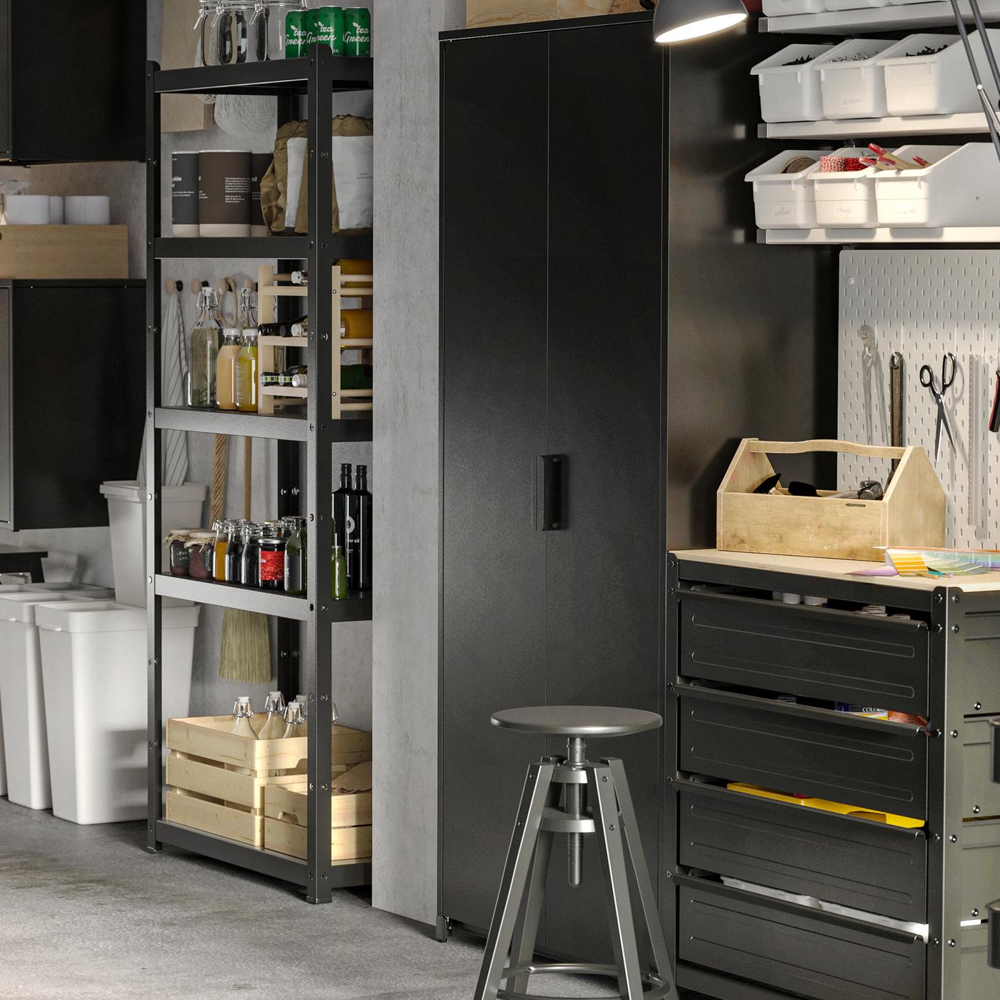 A garage with open and closed black cabinets. On the shelves are boxes and bottles. Underneath are recycling garbage cans.