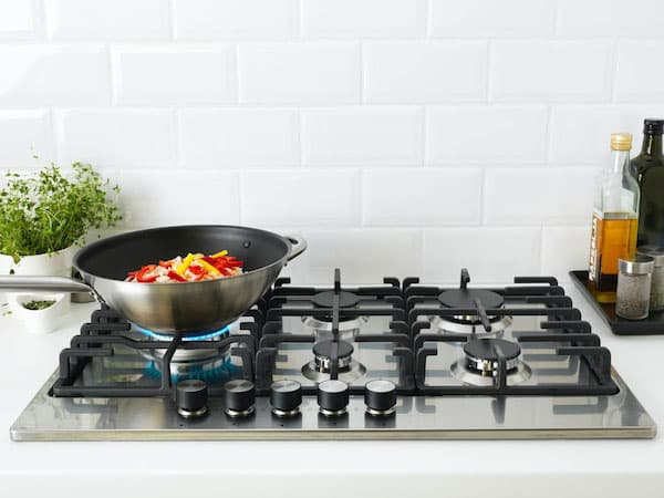 A gas hob in stainless steel with black rails.