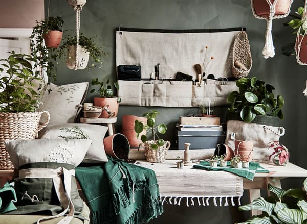 A gathering of BOTANISK products including baskets, textiles, plant pots, and hanging pouches in a room.