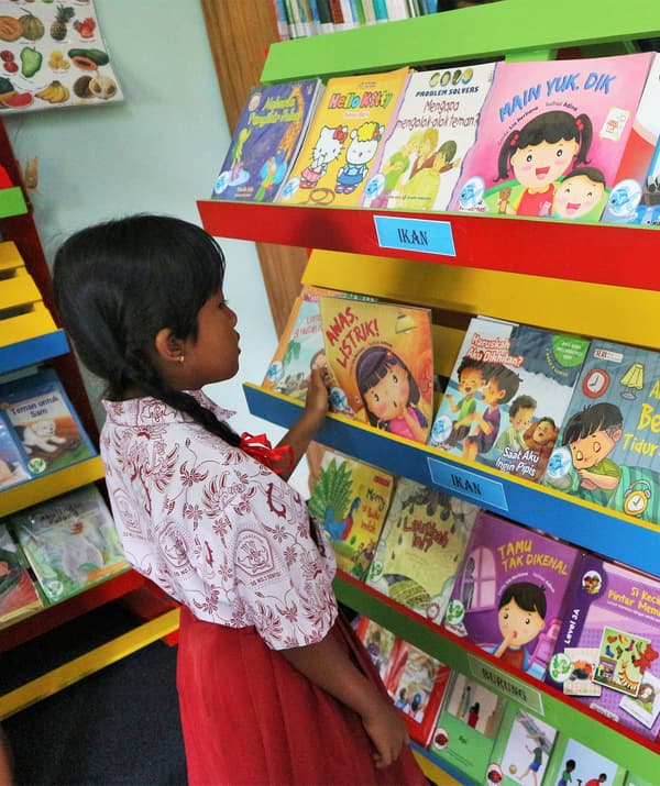 A girl choosing a book from a colourful reading library.