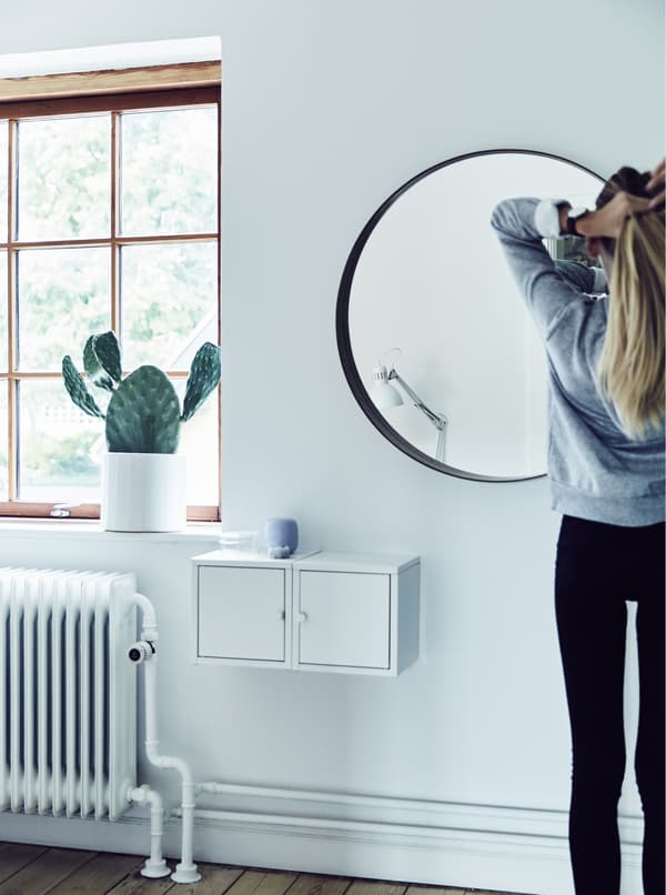 A girl doing her hair in the mirror.
