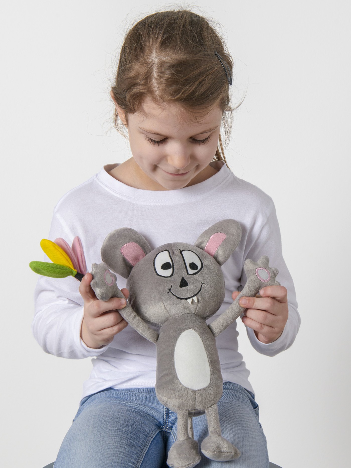 A girl holding gray mouse soft toy.