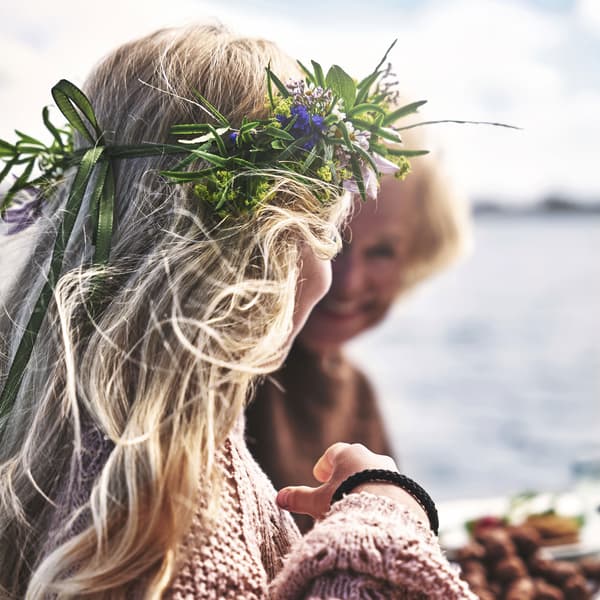 A girl is sitting at a table with a flower crown on her head.