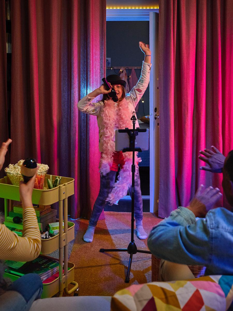 A girl performs in front of BLÅHUVA brownish-red block-out curtains.