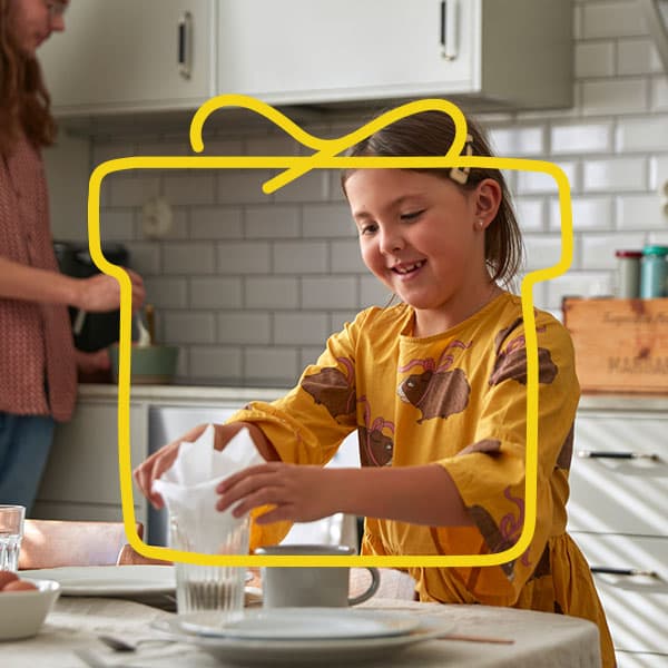 A girl setting the table in the kitchen.