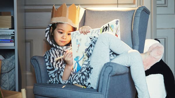 A girl sitting in a chair and drawing. 