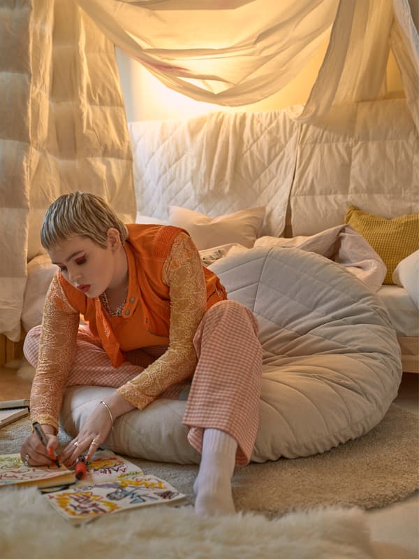 A girl sitting on a floor pillow to study.
