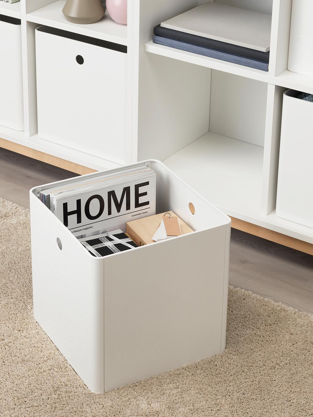 A girl standing holding two SAMLA boxes filled with toys and books.