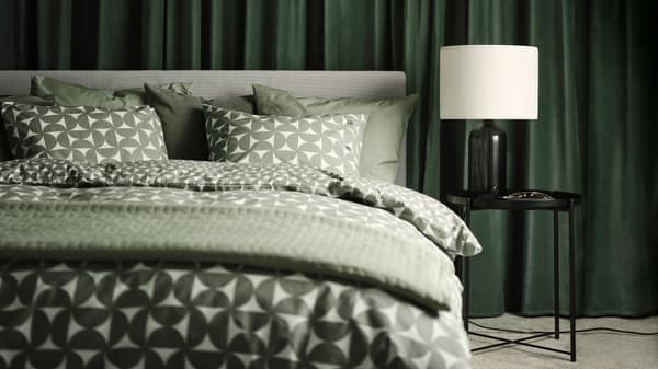 A GLADSTAD upholstered bed with four storage boxes dressed in grey/green ÄNGSNEJLIKA bed linen.