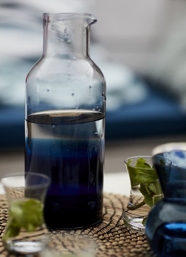 A glass carafe on a woven place mat.