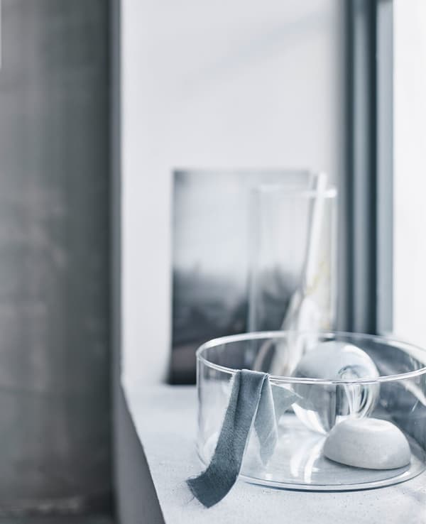 A glass vase on a windowsill with daylight shining in.
