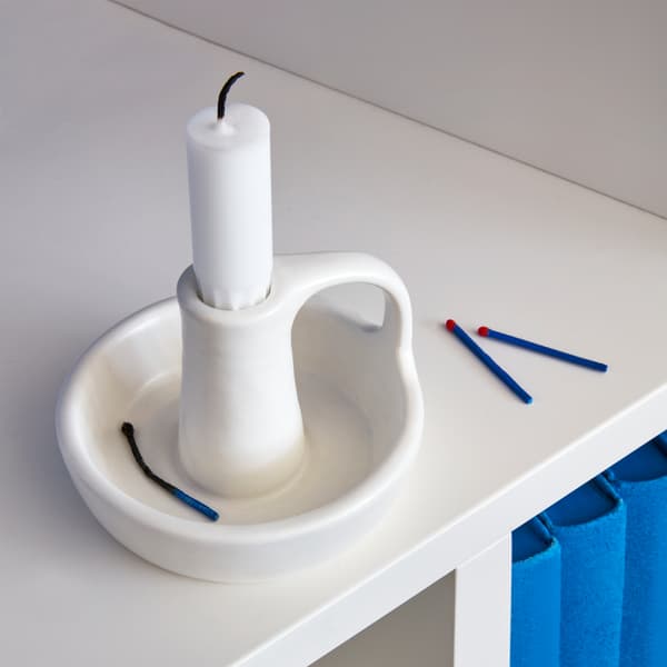 A GODTAGBAR candlestick designed in a traditional style with a handle, made in white stoneware.