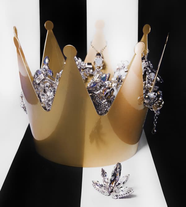 A gold crown-shaped bowl filled with diamond jewellery.