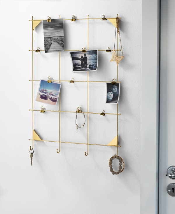 A gold memo board with clips holding jewellery and photographs.