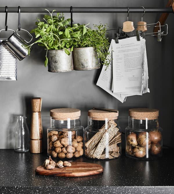 A granite effect worktop with glass storage jars holding nuts, onions and crispbreads