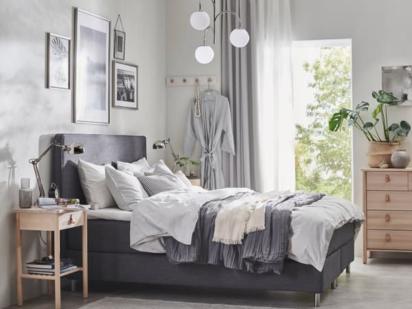 A gray DUNVIK ved draped with white and gray beddings in a brightly lit bedroom. A gallery wall over the bed.